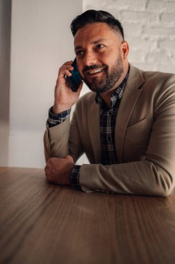 Kafede kahve içerken akıllı telefon kullanan yakışıklı bir işadamı.