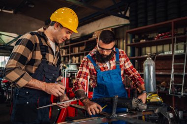 Yetenekli iş arkadaşları üretim için malzeme hazırlarken aynı zamanda mezura kullanıyor ve tüm noktaları öğütüyor. Alet ve makinelerle dolu bir tesiste ekip olarak çalışmak. - Evet. Boşluğu kopyala.