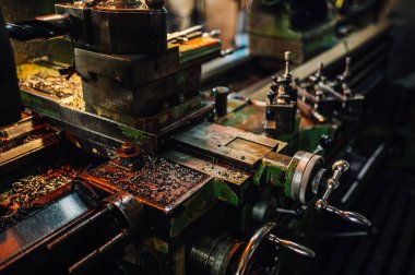 Sıkıcı ya da metal talaşı, çeşitli düğmeleri ve kolları olan bir torna makinesinin yakın plan görüntüsü. Değişik elementlerde aşınma gösteren yeşil bir makine parçası, boya kullanılmaktan kesilmiş. Geçerli.