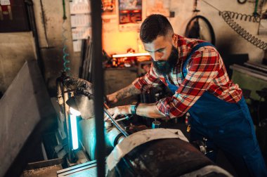 Torna makinesi üzerinde çalışan bir makinistin metal makine elementi üretmek için kullandığı bir resim. Yeni bir metal silindir monte ediyor. Bulanık arkaplan, fabrika.