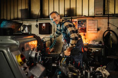 Eski bir fabrika tesisinde gülümseyen bir makinist ziyaretçiyi selamlıyor. Gülümsüyor, kameraya bakıyor. Mutlu bir makinist kameraya gülümserken ağır sanayi makinesini çalıştırıyor..