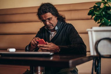 Üst düzey İspanyol Kübalı adamlar bir kafede çalışırken akıllı telefon kullanıyorlar.