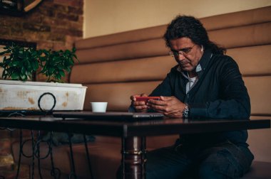 Üst düzey İspanyol Kübalı adamlar bir kafede çalışırken akıllı telefon kullanıyorlar.