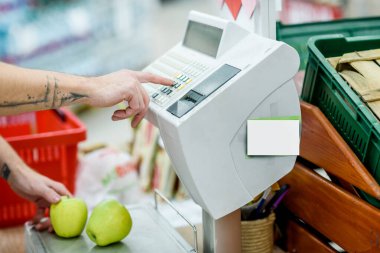 Süpermarkette meyveleri elektronik teraziye koyan adam.