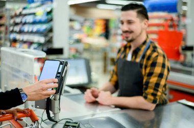 Kadın eli süpermarkette akıllı telefonuyla temas kurmadan ödeme yapıyor.