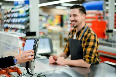 Kadın eli süpermarkette akıllı telefonuyla temas kurmadan ödeme yapıyor.