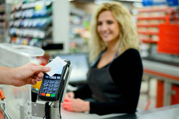 Close up shot of a mans hand making a contactless payment with his credit card at a supermarket