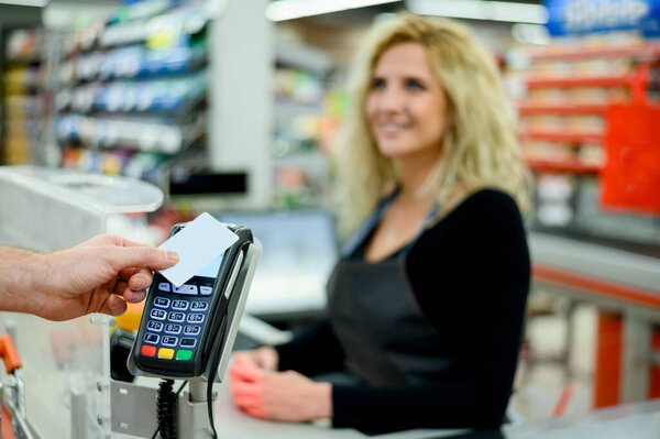 Close up shot of a mans hand making a contactless payment with his credit card at a supermarket