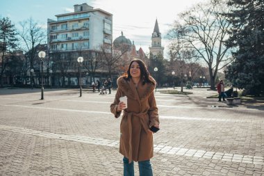 Genç bir iş kadınını akıllı telefon kullanarak şehirde kahve içerken çekmişler.