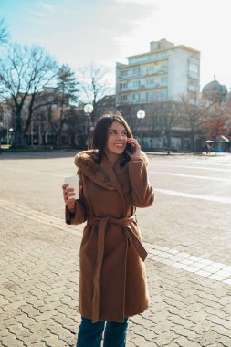 Şehirde kahve içerken akıllı telefondan konuşan İspanyol kadın.
