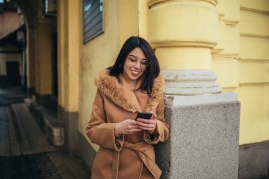 Genç İspanyol kadın şehirde yürürken akıllı telefon kullanıyor.