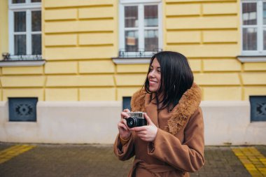 Genç İspanyol kadın şehirde retro kamera kullanıyor.