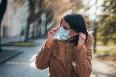 Salgın sırasında cerrahi maske takan genç ve güzel bir İspanyol kadının görüntüsü.