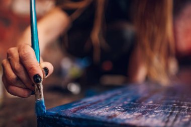 Boya fırçasıyla kadın ressam eli, damlayan resim, soyut renkli sıçrama ve vuruşlar. Resim atölyesinde el ele tutma kursu araçları.