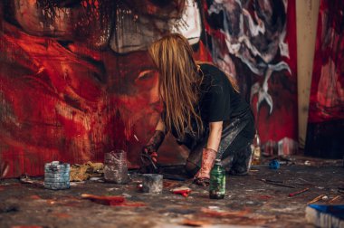 Yaratıcı pozitif kadın ressam, stüdyosunun soyut resmini büyük bir tuvale çiziyor. Yaratıcı bir sanat atölyesinde boyama işlemi. Sanatçı tutkusu.