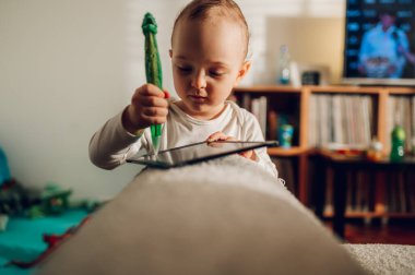 Sevimli küçük bir çocuk evde bir çizim tahtasıyla oynuyor. Bir çocuk evdeki bir çizim tahtasına karalama yapıyor. Bir çocuk yaratıcı olmayı öğreniyor. Sağlıklı gelişim kavramı.