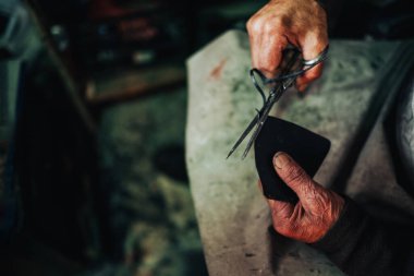 Eski bir kunduracının ellerini ayakkabıcısının atölyesinde makasıyla deri parçalarını keserken. Tanınmayan bir usta atölyesinde ayakkabı yapımı için deri parçalar hazırlıyor..