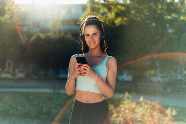 Şehirde çalışan genç ve güzel bir bayan sporcunun akıllı telefonunu kullanırken çekilmiş fotoğrafı.