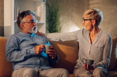 Evde bir kanepede oturup ciddi bir konuşma yaparken birbirlerine bakan son sınıf bir çiftin portresi. Modern iç mekan. Boşluğu kopyala.