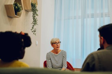 Kıdemli kadın grup terapisi hakkında konuşuyor ve bağımlılık ve akıl sağlığı sorunlarını tartışıyor. Olgun bir kadın zihinsel sağlık sorunları hakkında konuşuyor ve destek arıyor. Boşluğu kopyala.