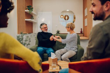 Psikolog ofisinde el ele tutuşan son sınıf öğrencilerinin portresi kişisel sorunları tartışırken ve başkalarını dinlerken bakış açılarını paylaşırken. Psikolojik destek alıyorum. Boşluğu kopyala.