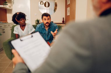 Evlilik terapisi ve aile terapisti muayenehanesinde çeşitli çiftlerin ilişki sorunları var. Genç çok ırklı insanlar profesyonel psikologların yardımıyla anlaşmazlığı çözmeye çalışıyorlar..