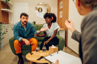 Evlilik terapisi ve aile terapisti muayenehanesinde çeşitli çiftlerin ilişki sorunları var. Uzman psikologların yardımıyla çatışmaları çözmeye çalışan çok ırklı insanlar..