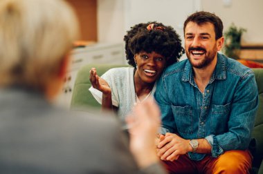 Ofisteki bir psikologla seans sırasında sarılıp gülümseyen çok ırklı genç bir çift. Çeşitli eşler yardım için profesyonel terapiste gidiyorlar. Afro-Amerikan bir kadına odaklan..