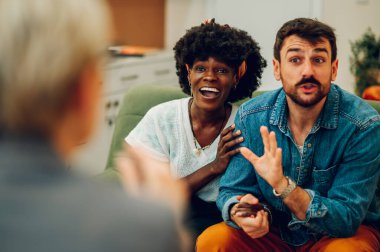 Gülümseyen çeşitli sevgili ve sevgili ya da eşlerin terapistle ya da bir ofiste psikologla buluşması. Gülümseyen ve sarılan mutlu Afro-Amerikan bir kadına odaklan..