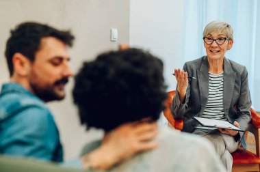 Üst düzey bir kadın danışmanın portresi terapi seansında tanınmayan bir çifti dinliyor. Akıl sağlığı. Olgun psikiyatrist evlilik sorunları olan bir çiftle seans yapıyor..
