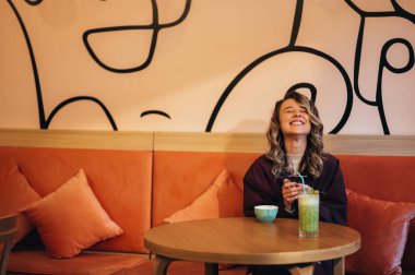 Kahve içen ve kafede akıllı telefon kullanan güzel genç bir kadın.