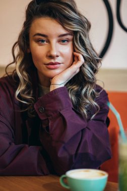 Kafede kahve içen genç ve güzel bir kadının portresi.