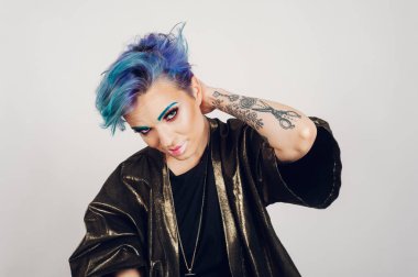 Sağlıklı nemlendirilmiş pürüzsüz bir teni ve beyaz stüdyo arka planında parlayan renkli makyajı olan güzel beyaz bir kadın. Moda, güzellik ve makyaj portresi. Dövmeli kadın..