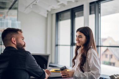 Erkek ve bayan meslektaşlar, toplantı sırasında bilgisayar kullanırken online yazılım stratejilerini tartışıyor ve iş birliği yapıyorlar. Ofis arkadaşları birlikte proje planlıyor.