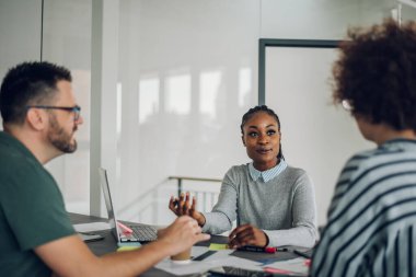 Ofisteki toplantı sırasında üç farklı iş ekibi analitik belgeleri kullanarak projeleri tartışıyor ve planlıyor. İş ve finans kavramı. Güzel bir Afro-Amerikan iş kadınına odaklan..