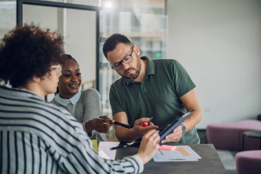Ofiste bir toplantı sırasında tablet kullanırken üç farklı iş ekibi proje tartışıyor ve planlıyor. İş ve finans kavramı. Çok ırklı iş arkadaşları belgeleri kontrol ediyor.