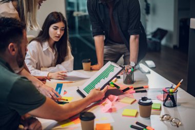 Modern bir şirketin toplantı odasında birlikte çalışan yaratıcı iş ekibi. Beyin fırtınası konsepti. Ofis hayatı. Elinde çizelge olan bir adama odaklan..