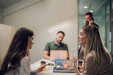 Modern bir ofiste eğlenceli ve genç yaratıcı insanlar. Yaratıcı ortak çalışma alanında birlikte çalışan bir grup iş adamı. Eğlenceli insanlarla çalışmak. Konuşan iki bayan meslektaşına odaklan..