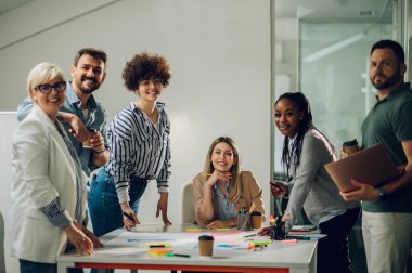 Çeşitli ofisteki neşeli insanlar ekip çalışmasını konuşarak ve eğlenerek yapıyor. Çok ırklı iş arkadaşları ofiste beyin fırtınası yaparken eğleniyor. Takım çalışması konsepti.