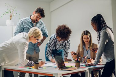 Çeşitli çalışanlar, beyin fırtınası sırasında ofiste toplanarak yeni projeleri için yeni fikirleri tartıştılar. Çok ırklı iş arkadaşları toplantı odasında toplanıp toplantıda fikir alışverişinde bulundular.