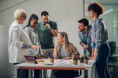 Modern, aydınlık ofis içi bir toplantıda çok ırklı bir iş ekibi kuracağız. Kadın takım lideri çeşitli meslektaşlarına projesini sundu.