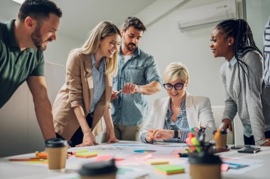 Çeşitli ofisteki neşeli insanlar ekip çalışmasını konuşarak ve eğlenerek yapıyor. Çok ırklı iş arkadaşları ofiste beyin fırtınası yaparken eğleniyor. Takım çalışması konsepti.