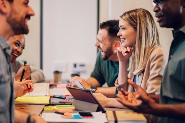 Çeşitli ofisteki neşeli insanlar ekip çalışmasını konuşarak ve eğlenerek yapıyor. Çok ırklı iş arkadaşları ofiste beyin fırtınası yaparken eğleniyor. Beyaz bir kadına odaklan..