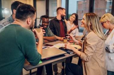 Bir grup çok ırklı genç meslektaşın toplantı odasında şirket projeleri hakkında konuşuyorlar. Takım çalışması konsepti. Çeşitli iş arkadaşları birlikte çalışıyor..