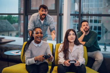 Neşeli çeşitli iş arkadaşları TV konsolunda video oyunları kazanıyor. İşten sonra ofiste joystickle oynuyorum. Mutlu insanlar ofis partisinde eğleniyorlar..