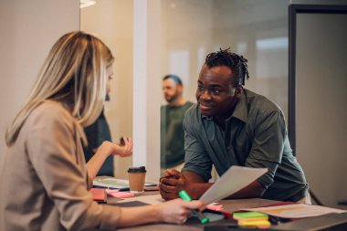 İki farklı iş adamı bir ofiste sohbet ediyorlar. Heyecanlı beyaz kadın fikirleri paylaşıyor ya da siyahi erkek iş arkadaşıyla iş planı yapıyor. İş molası kavramı. Çok ırklı takım.