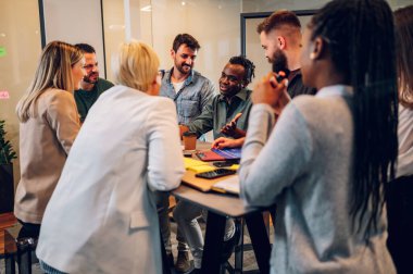 Bir grup çok ırklı genç meslektaşın toplantı odasında şirket projeleri hakkında konuşuyorlar. Takım çalışması konsepti. Çeşitli iş arkadaşları birlikte çalışıyor..