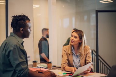 İki genç çok ırklı iş adamı ellerinde tuttukları belgelerden bahsediyorlar. İki farklı iş arkadaşı açık bir uzay ofisindeki toplantı sırasında tartışıyorlar..