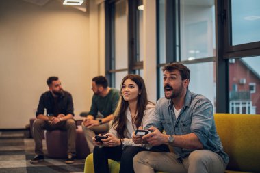 Erkek ve kadın iş arkadaşları iş molasında ofiste video oyunu oynuyorlar. Arkadaş canlısı bir atmosferde birlikte çalışan meslektaşlar..