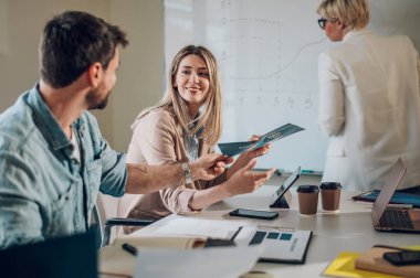 Ofisteki neşeli insanlar ekip çalışmasını konuşarak ve eğlenerek yapıyor. Mutlu iş arkadaşları ofiste birlikte çalışırken eğleniyor. Takım çalışması konsepti. Güzel sarışın bir kadına odaklan..